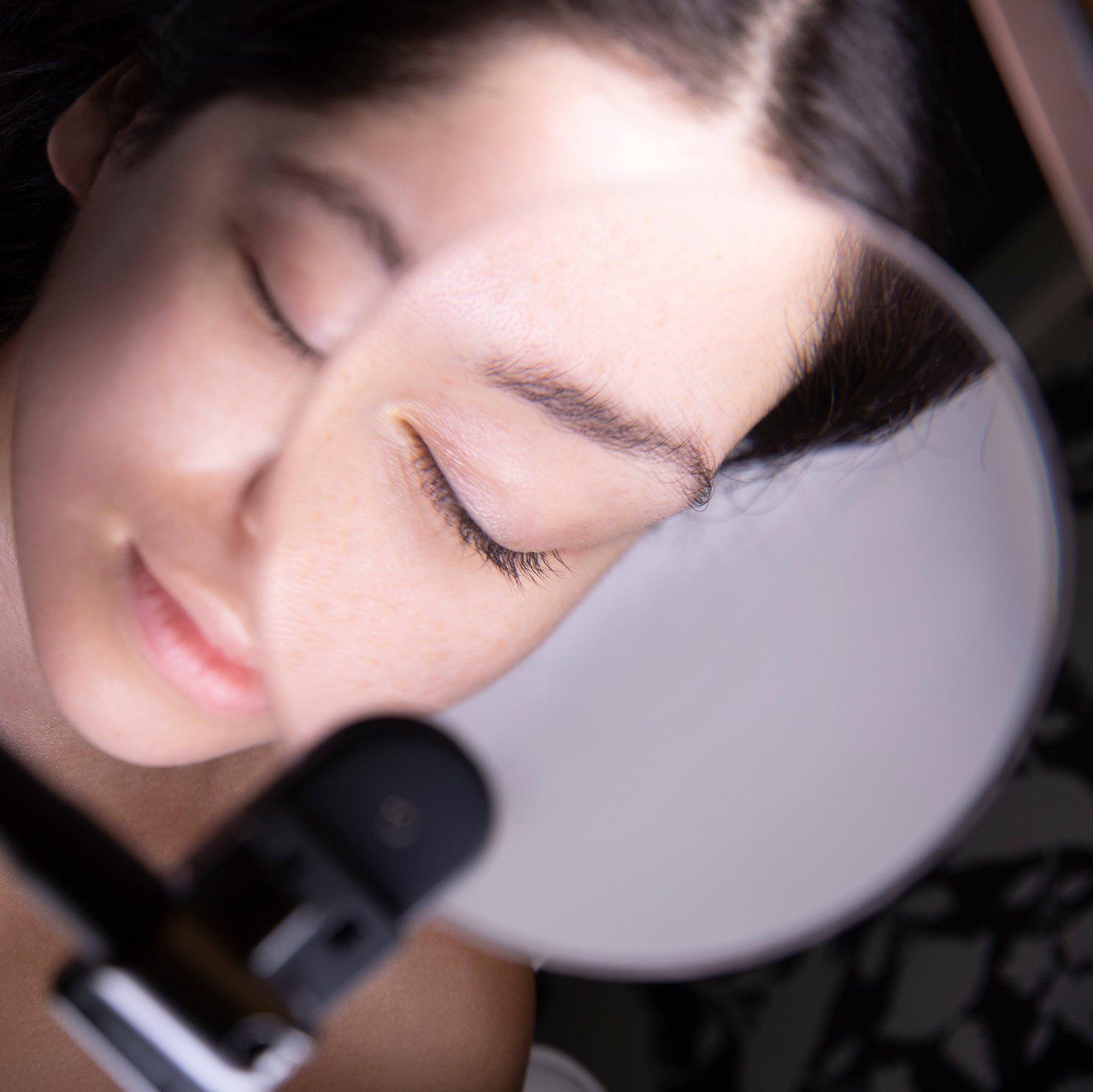 Glamcor Magnifying Glass Accessory converting a mirror into a portable magnifying lamp for detailed work.