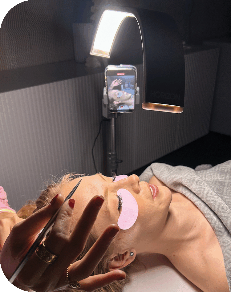 A close-up of an esthetician's hands performing a treatment under the bright and focused light of the portable GLAMCOR horizon.