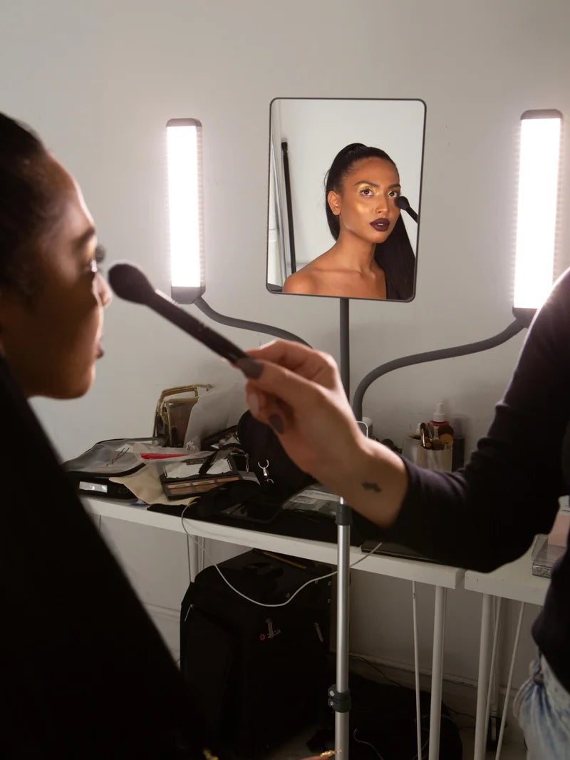 Makeup artist applying makeup to a client lit by the MULTIMEDIA X, with the client reflected in the mirror